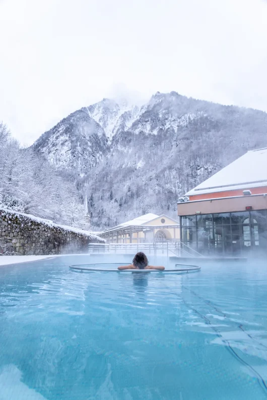 Photo d'une femme dans un bain d'eau chaude avec les montagnes en paysage